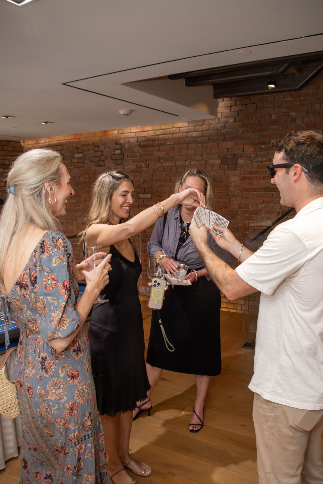 A guest reaches for a card from a fanned deck while her friends laugh at a private event.