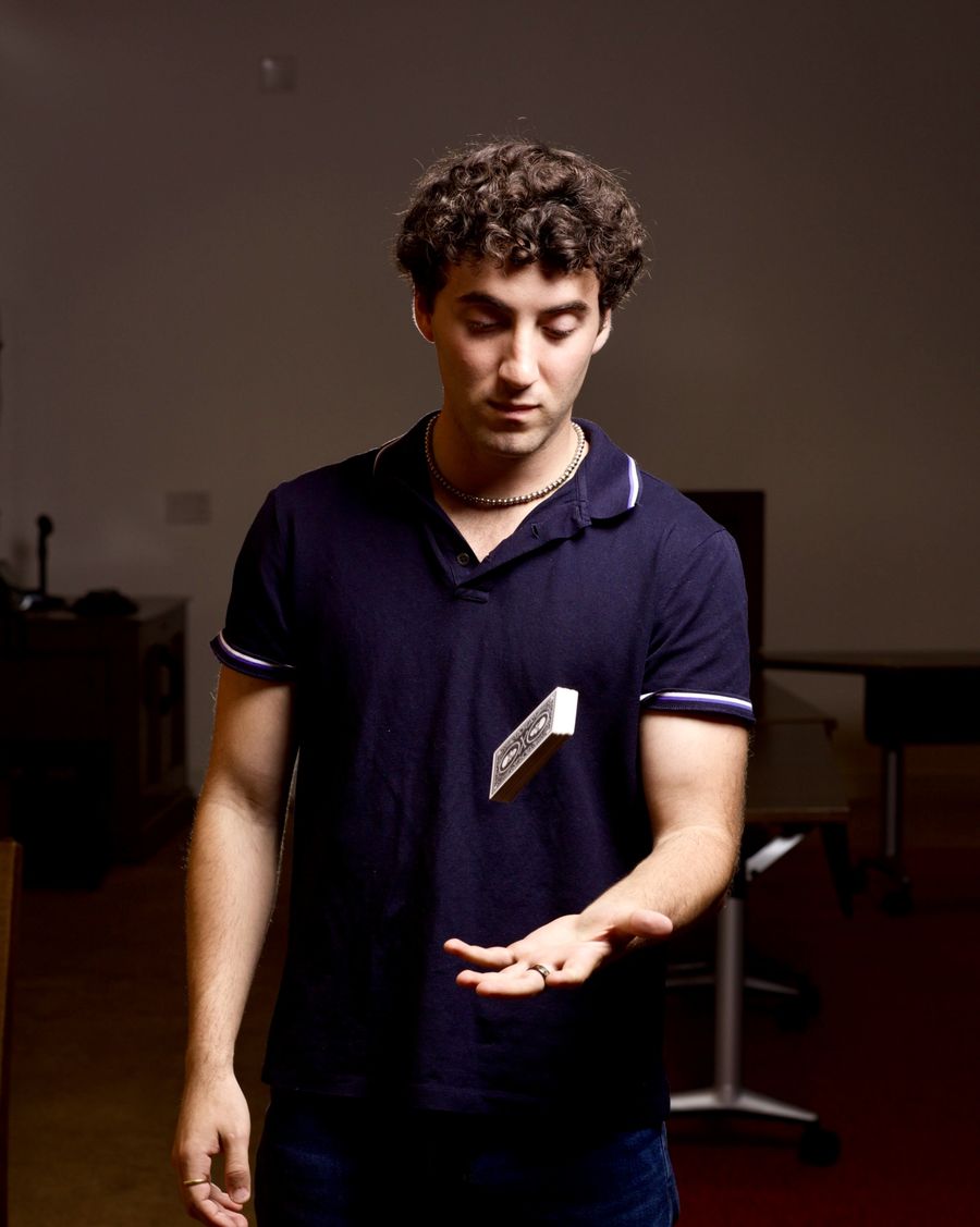 Tyler Gibgot looking down at a deck of cards suspended in mid-air above his open palm.