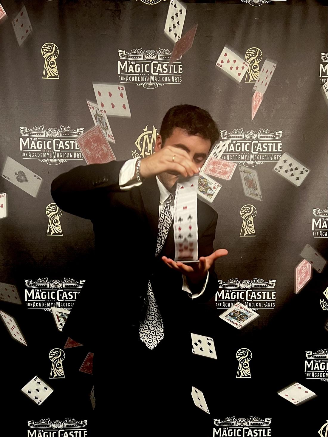Tyler Gibgot in a suit at the Magic Castle, cascading a deck of cards from one hand to the other.