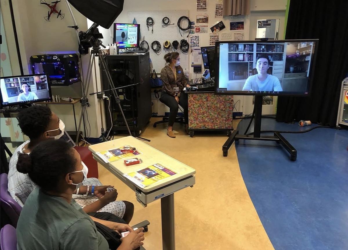 Patients and families in the KidZone TV studio watching Tyler perform magic live on a large screen.