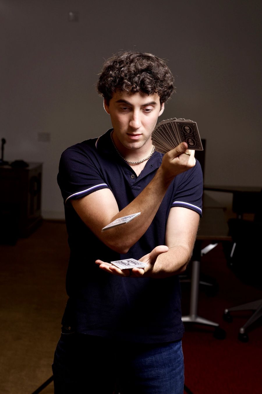 Tyler Gibgot holding a fanned deck in one hand while a single card hovers above his open palm.